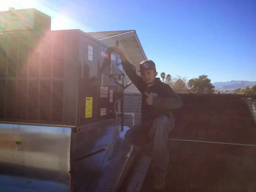 HVAC technician performing Air Duct Cleaning on a rooftop unit in Norwich