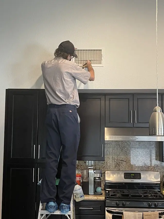 Technician inspecting an air vent during HVAC service in Norwich